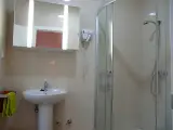 En-suite bathroom with pedestal basin, lit mirror, hairdryer and glass shower with green towel